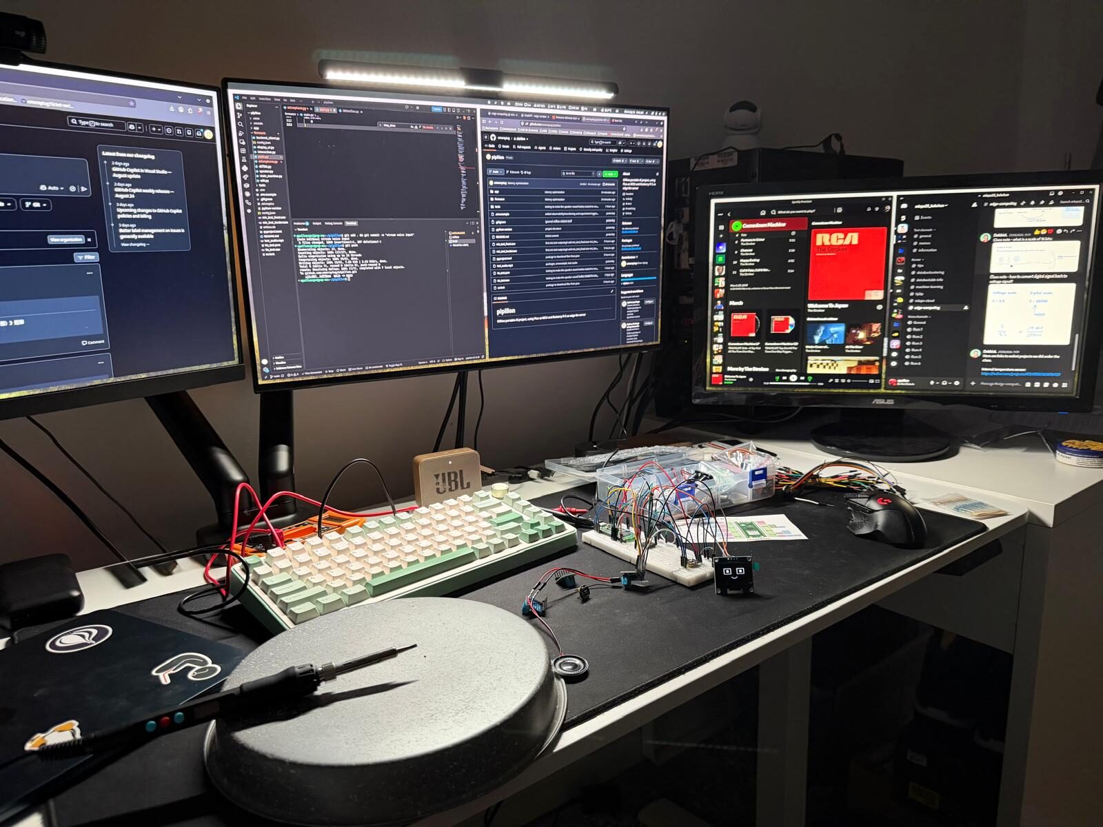 My desk in the middle of the build: breadboard with the Pico and the OLED face, a soldering iron, and a lot of wires.